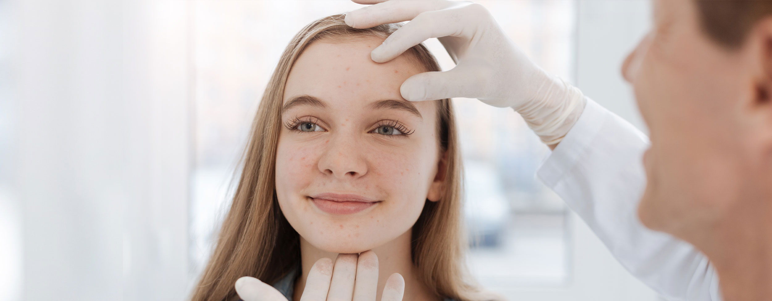 Dermatology clinician examining a patient's face